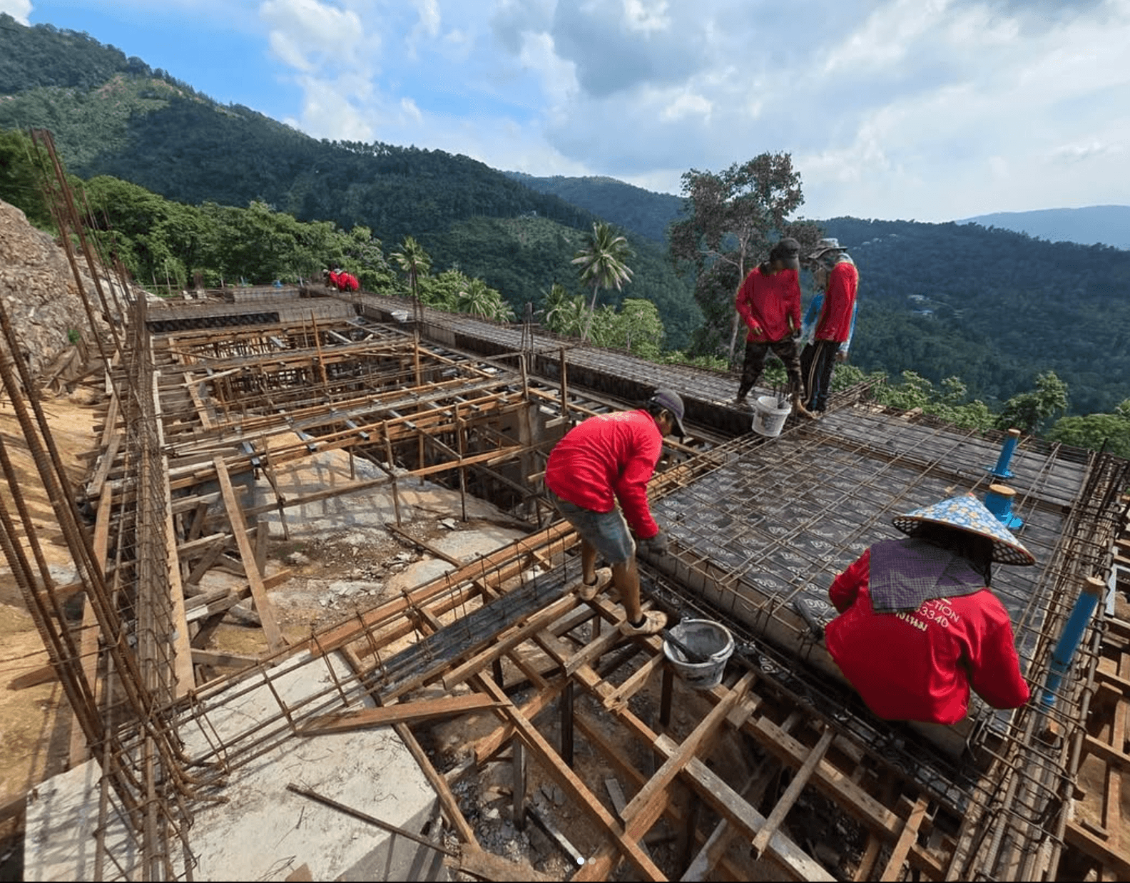 Construction crew working on reinforced concrete foundations in a mountain setting